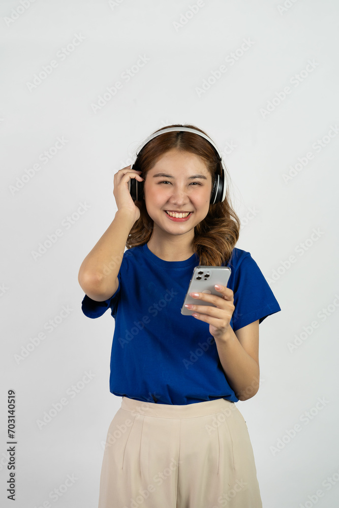 Excited smiling Asian woman holding mobile phone and looking happy standing on white background. Excited smiling Asian woman holding mobile phone and looking happy standing on white background.