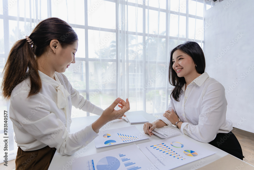 Two Asian female accountants have team meeting to summarize financial information in business office, creative female executive using tablet PC and smiling Two Asian female accountants have team meeting to summarize financial information in business office, creative female executive using tablet PC and smiling