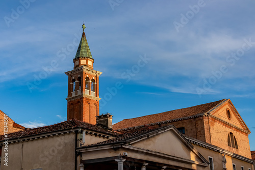 Close up view at sunrise of bell tower of Church of Saint James Apostle nestled in charming town of Chioggia, Venetian Lagoon, Veneto, Italy. Sightseeing in historic old town of Chioggia. Sightseeing © Chris