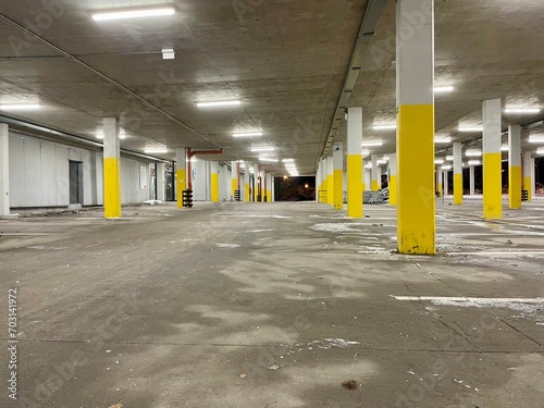 An empty parking lot at night, lit by fluorescent lights. Rows of columns with yellow paint. A solution to the city's parking problem. High quality photo