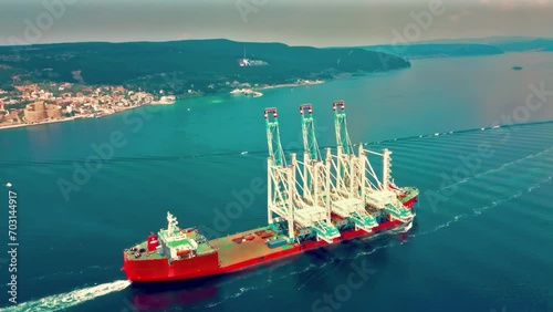 Drone view of cargo ship carrying giant cranes