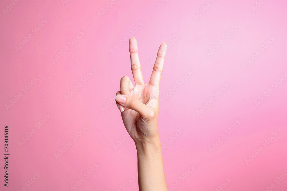 Hand showing two fingers isolated on pink background, victory and peace gesture - obrazy, fototapety, plakaty 