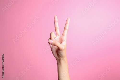 Hand showing two fingers isolated on pink background, victory and peace gesture
