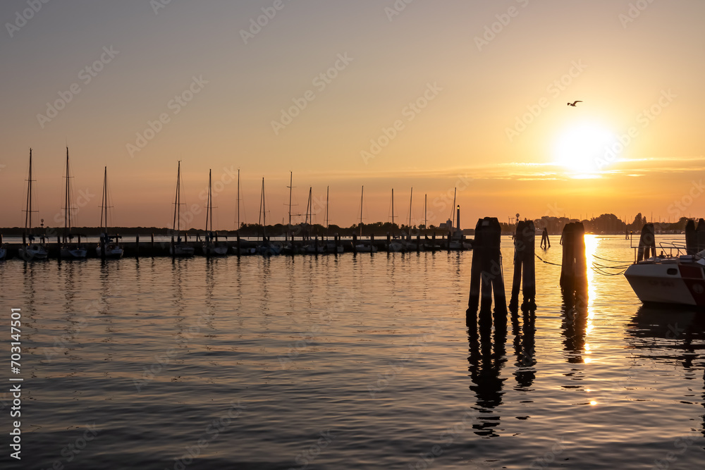 Beautiful sailing boats in picturesque port of  charming town of Chioggia at sunrise, nestled in the stunning Venetian Lagoon of the Veneto region in Italy. Tranquil atmosphere in summer