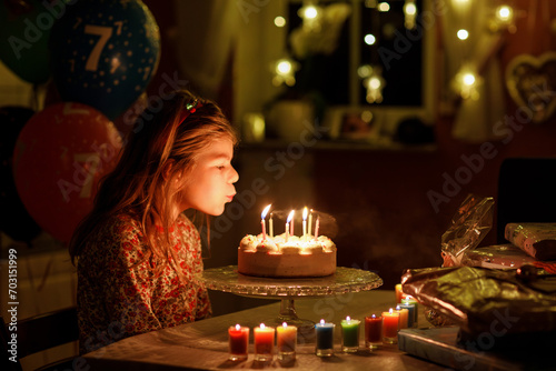 Happy little girl celebrating birthday. Cute smiling child with homemade princess cake, indoor. Happy healthy preschool kid blowing seven candles on cake photo
