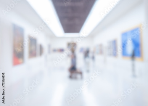 Blurred photo scene of art exhibition at gallery or museum with paintings and people  room decoration. Abstract blur background of white clean modern hall building.