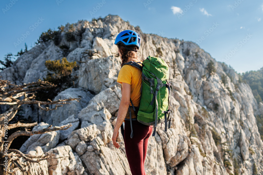 A girl with a backpack on a hike. adventure in the mountains. hiking with a backpack. girl with a backpack in the high mountains. Rock climbing and mountaineering concept.