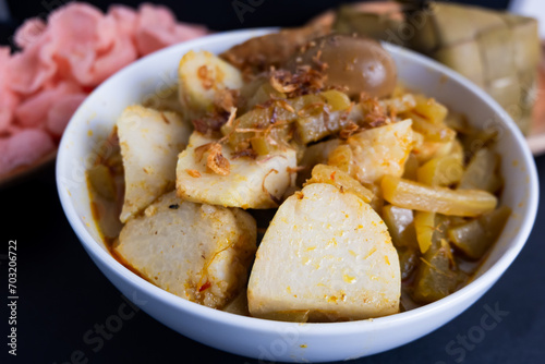 Ketupat Sayur or Lontong Sayur, a typical Indonesian food. Served with pumpkin vegetables, boiled eggs and tofu stew and crackers. Served during Ramadan, Eid al-Fitr and Adha. Black Background
