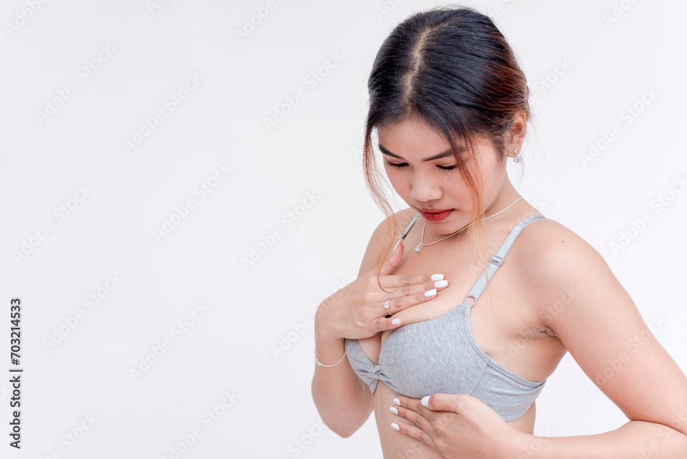A young woman feels her breast for any suspicious lumps. Detecting tumors or potential cancer. Wearing just a gray bra. A young woman feels her breast for any suspicious lumps. Detecting tumors or potential cancer. Wearing just a gray bra.