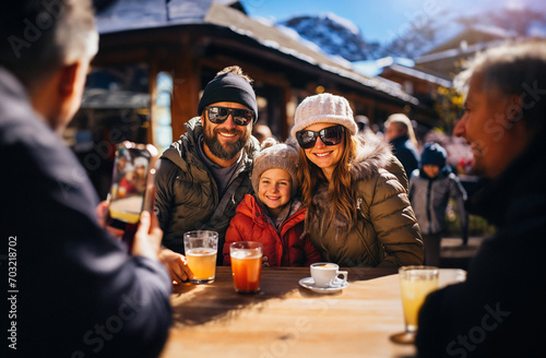 Family on vacation in the mountains, sharing a drink with friends in a good mood, on a terrace. At the background, the snow-capped mountains. Generative ai