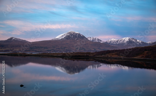 Sun setting over Beinn Alligin, mountains in Torridon, with natural water reflection on the loch © Sarah