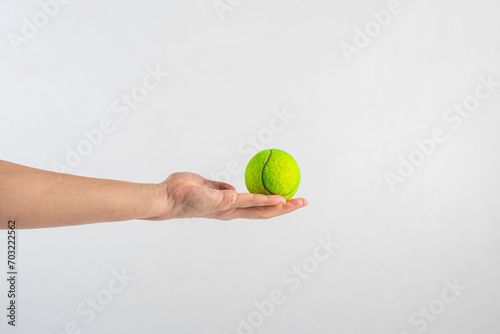 Tennis ball in hand on white background. © apinya