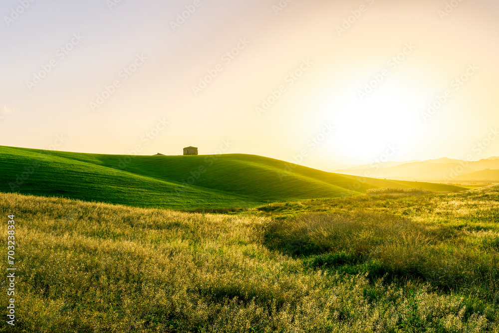 beautiful sunset or sunrise in rural countryside green hills with farm and mountains on background