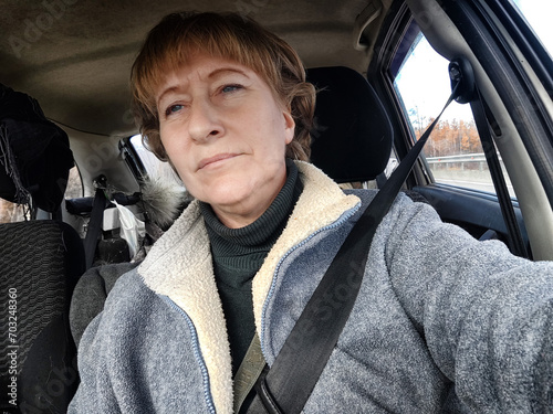 Portrait of female driver in solo journey. Adult mature woman holding steering wheel and looking through windscreen in travel by vehicle on vacation. Lady girl who is owner or rent a car for travel