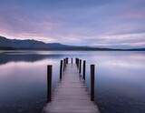 a long dock that is sitting in the water with mountains in the background