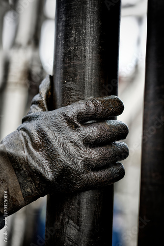 Human hand wearing a pair of gloves on oily drilling pipe photo
