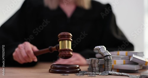 Judge knocks gavel with cash and coins and stacks of dollars on table photo