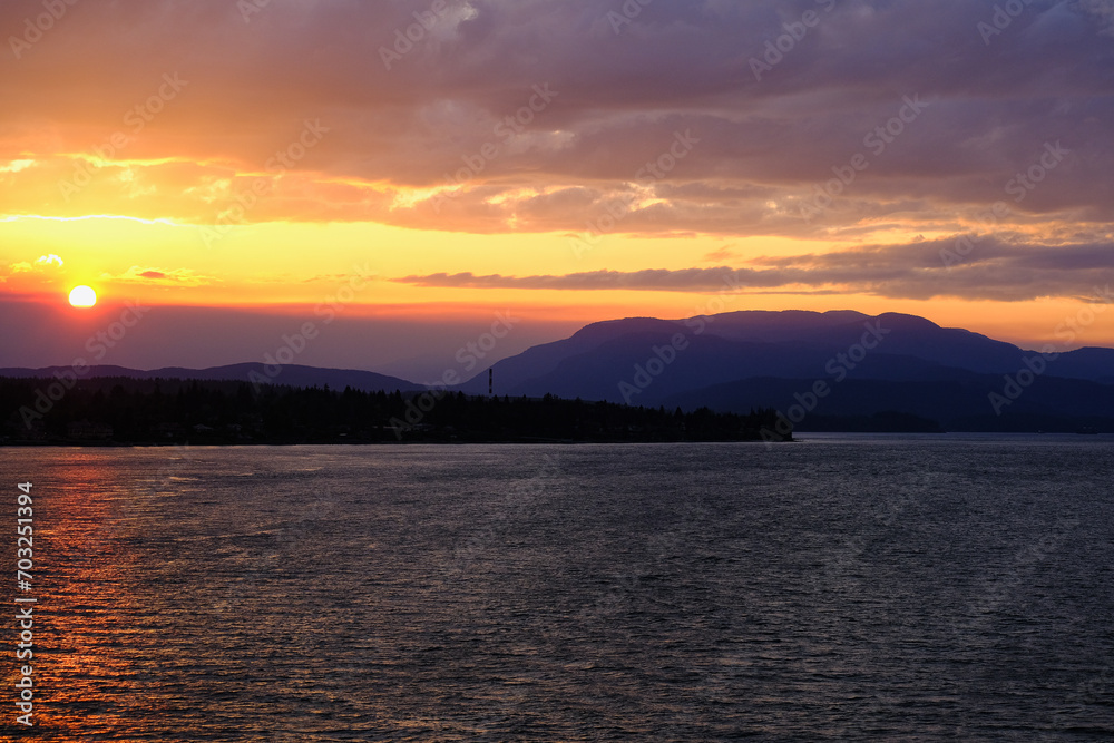 Fototapeta premium Panoramic sunrise or sunset landscape nature coastal scenery with beautiful fire sky and dramatic cloudscapes in Alaska Inside Passage glacier mountain range view