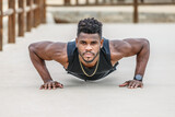 Motivated black sportsman doing push ups in park