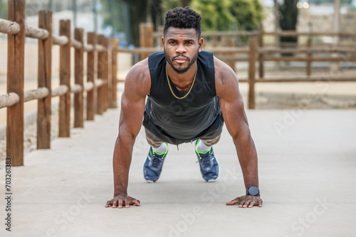 Strong sportsman doing plank in city park