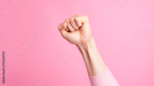 a woman fist against on pink background, girl power.
