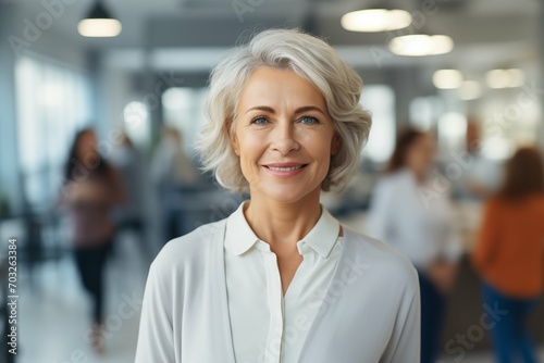 Portrait of a mature businesswoman working in a modern office and looking at the camera. Middle-aged woman, smiling handsome business woman entrepreneur