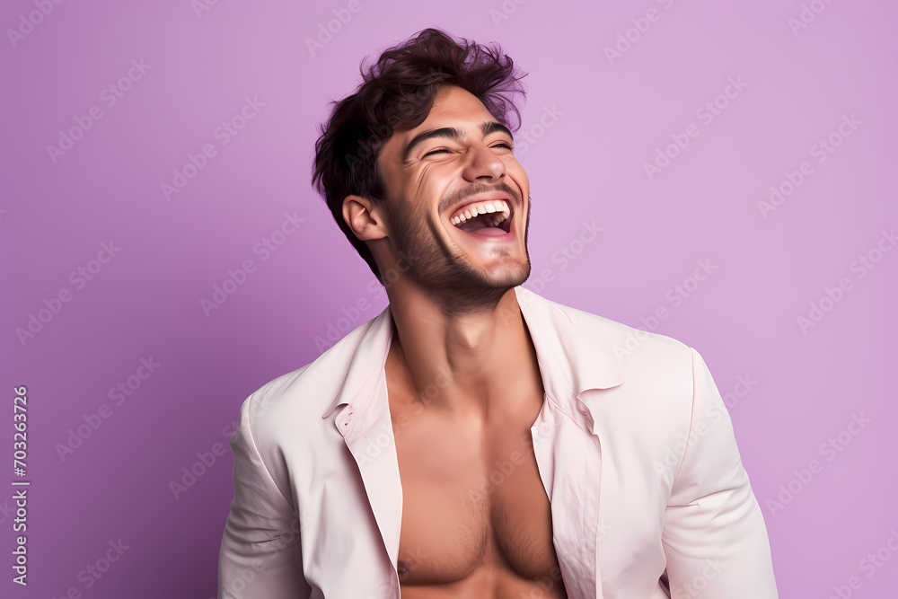 An exuberant male model laughing heartily against a soft lavender pink background. An exuberant male model laughing heartily against a soft lavender pink background.