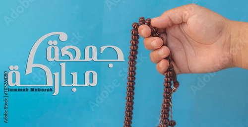 Jummah Mubarak blessed happy Friday Arabic Modern calligraphy, Selective focus image hand of Muslim woman holding prayer beads. photo