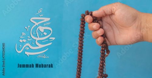 Jummah Mubarak blessed happy Friday Arabic Modern calligraphy, Selective focus image hand of Muslim woman holding prayer beads. photo