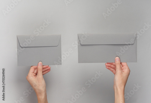 Hands holding envelopes on gray background photo