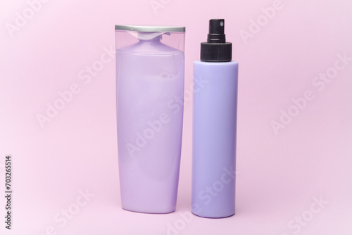 Shampoo and spray bottles on purple pastel background