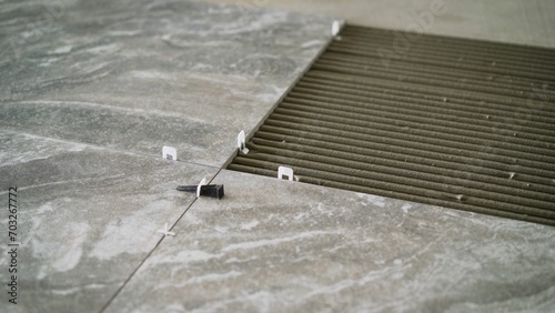 Laying tiles on the floor indoors. Ceramic tiles lie on the floor close-up. Laying floor tiles. Applying mortar for laying tiles. Large format floor slabs.