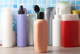 Many different shampoo and other cosmetic product bottles on a tile background