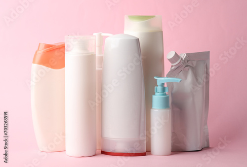 Many different shampoo and other cosmetic product bottles on pink background