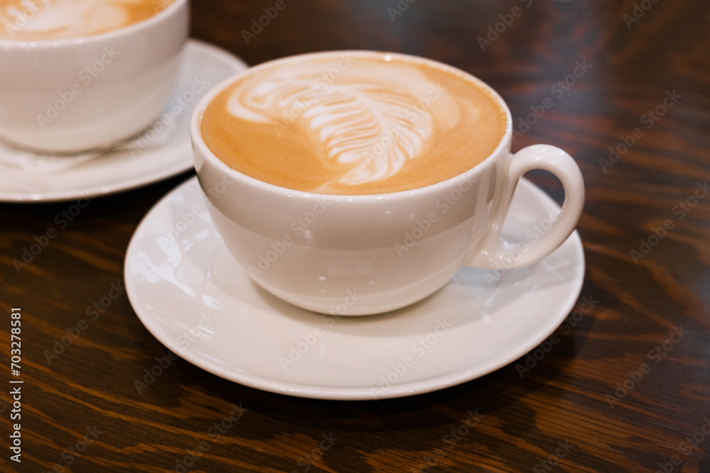 A cup of coffee on the table. Freshly brewed latte coffee on a brown wooden table. A cup of coffee on the table. Freshly brewed latte coffee on a brown wooden table.