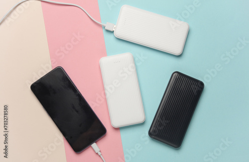 White power banks with smartphone on pastel background. External batteries for charging smartphone and other gadgets.