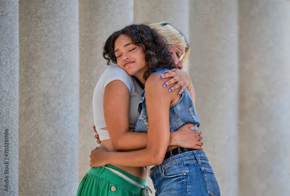 lesbian latin brunette and caucasian blonde standing hugging each other with eyes closed