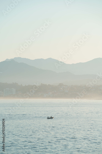 Peaceful fisherman in his boat searching for fish during morning in a landscape background