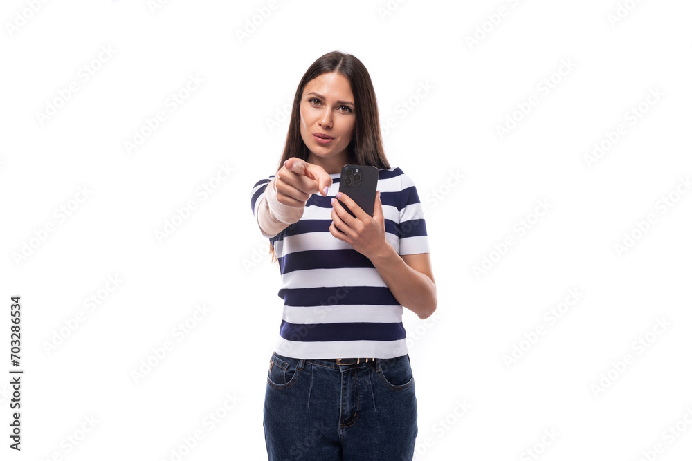 young brunette woman model dressed in a striped t-shirt and jeans makes a photo on a smartphone young brunette woman model dressed in a striped t-shirt and jeans makes a photo on a smartphone