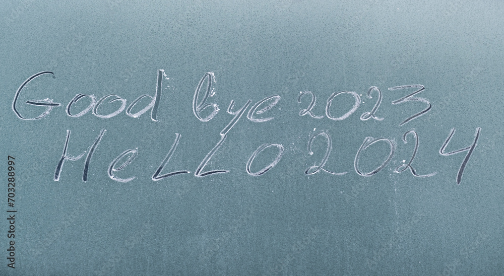 Fototapeta premium the inscription on the frozen glass: “Goodbye 2023, hello 2024.” Christmas background. Christmas background with frost on glass. 