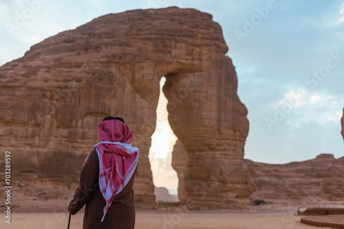 Man in desert looking at Al Ula most attractive place known as Elephant Rock which is situated in Saudi Arabia. One among the famous tourist attraction in Saudi Arabia.