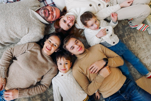Top view of happy big multi-generation family lying in circle on floor and smiling at camera