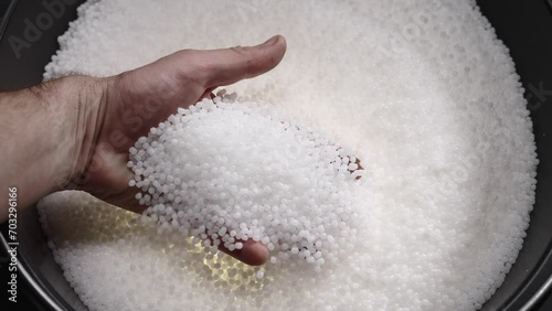 A factory worker checks plastic pellets before they are put into production. White compound in a man's hand. Production photo