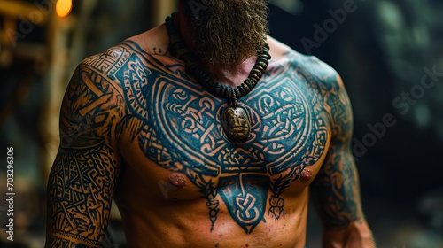 The man, with a powerful torso adorned with extensive tattoos of Celtic and tribal motifs, wears a massive necklace