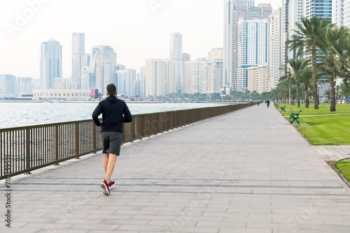 Urban man runner running on waterfront in city.