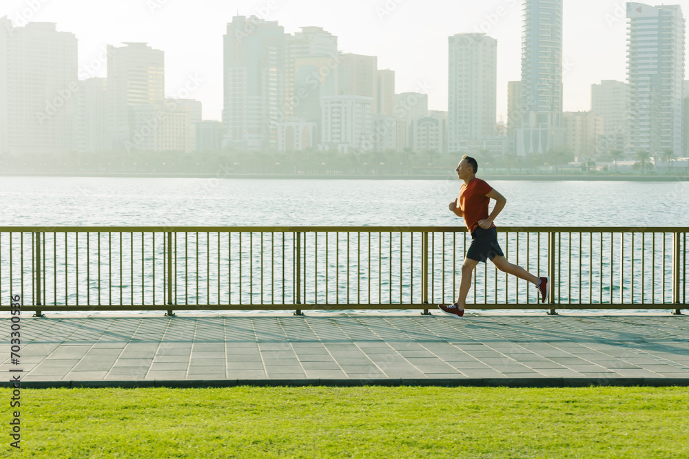senior man in sportswear jogging running outside on the seaside concrete road in front of city skyline at sunrise senior man in sportswear jogging running outside on the seaside concrete road in front of city skyline at sunrise
