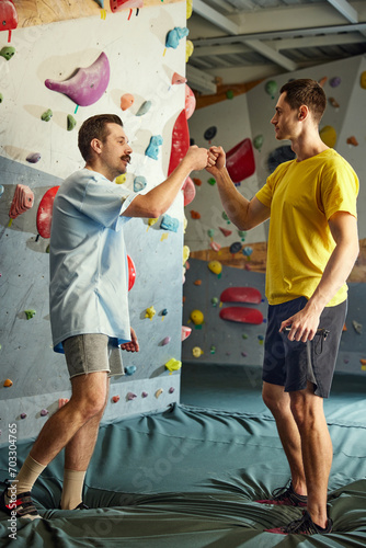 Young man visiting bouldering training course, greeting with instructor. Active hobby and extreme sport. Concept of sport, bouldering, sport climbing, hobby, active lifestyle, school, training course