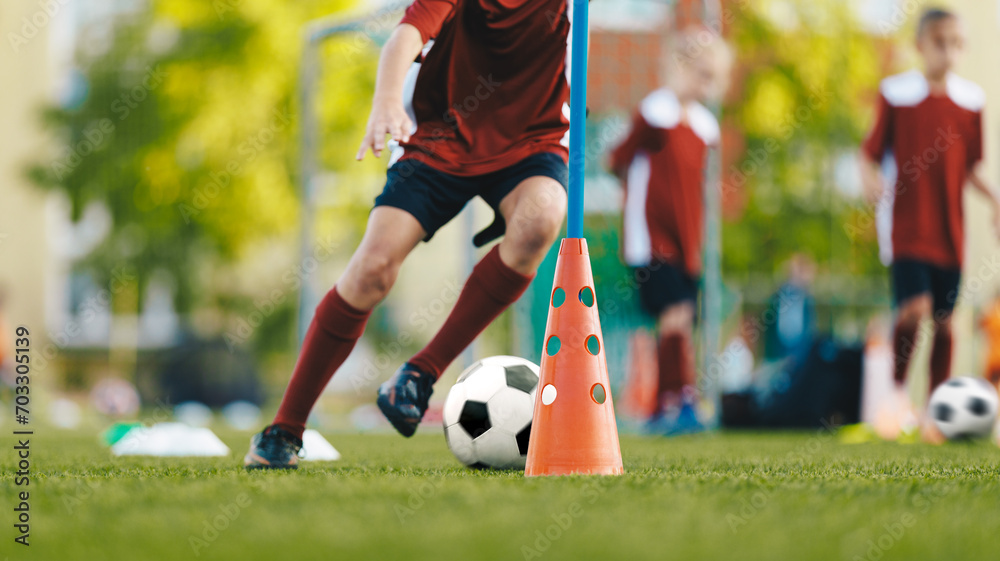 Youth in sports training. Player kicking ball during a soccer training drill. Slalom practice for football players. Summer sports practice camp for school kids - obrazy, fototapety, plakaty 