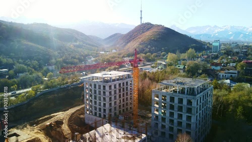 An aerial view of the construction of a residential building. The footage shows the activity of construction workers and heavy machinery. The boom of a large tower crane, metal structures and concrete photo