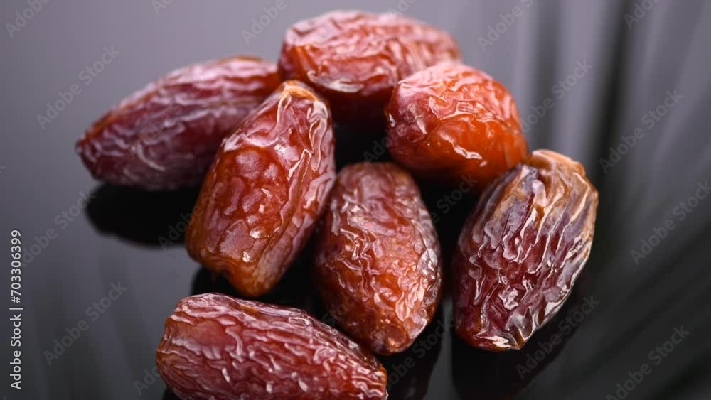 Dates fruit. Date fruits with palm tree leaf reflection on black background. Heap of Medjool dates close up.   